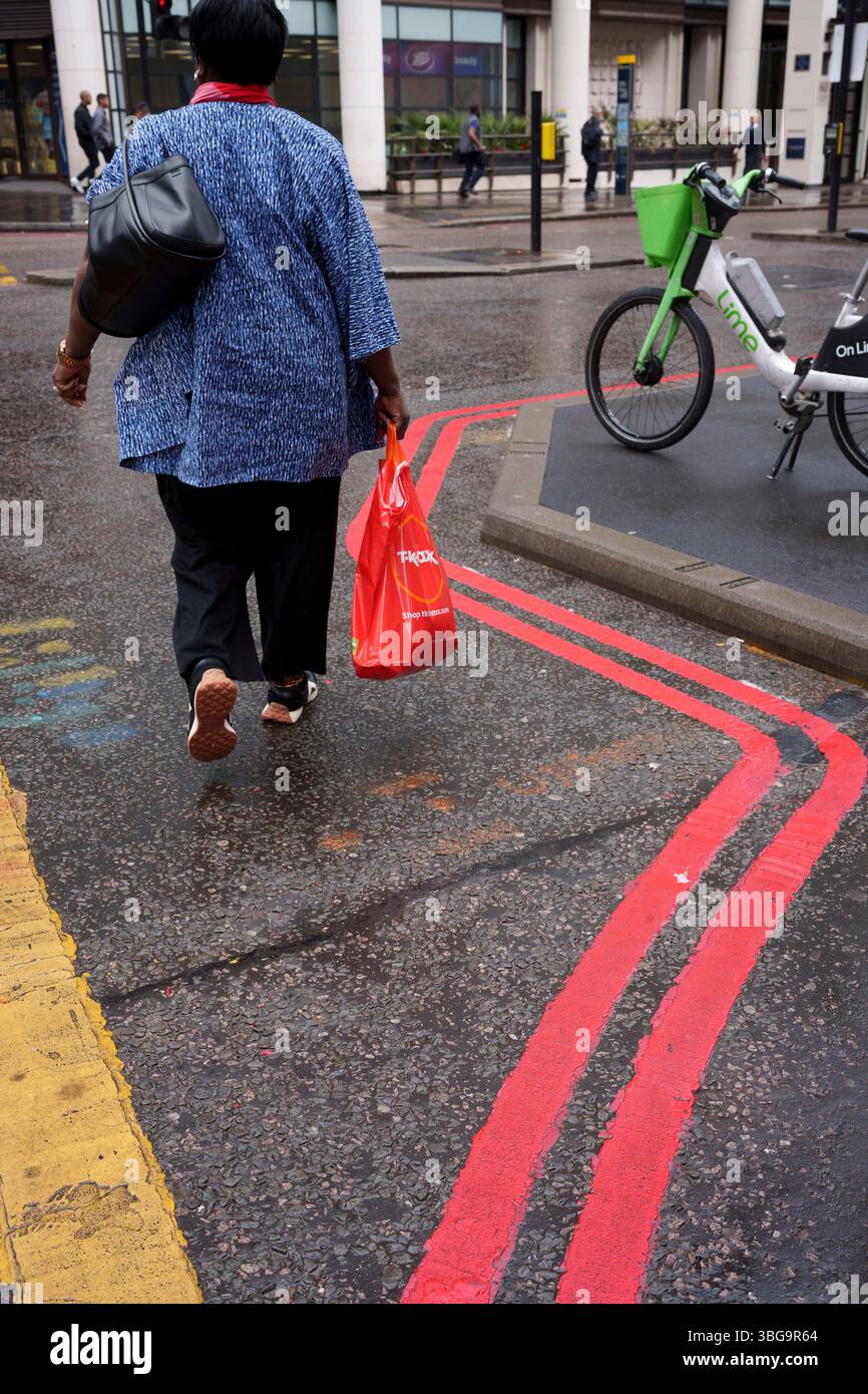 Un acheteur traverse les lignes de jonction Red route et Box sur Gracechurch Street dans la ville de Londres, le quartier financier de la capitale, le 3 juin 2025, à Londres, en Angleterre. Banque D'Images