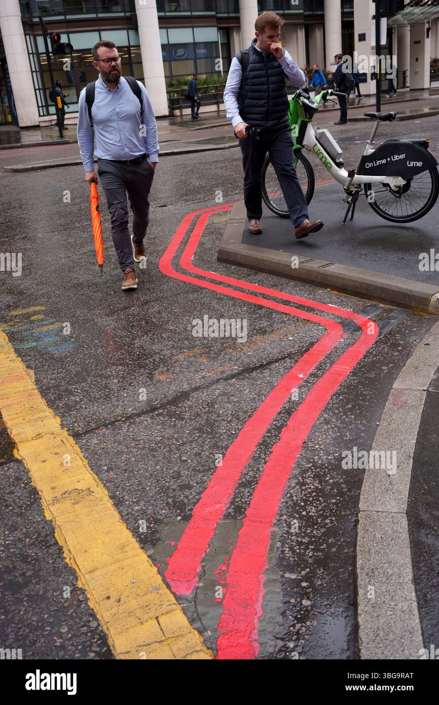 Deux piétons passent devant les lignes de la route Rouge sur Gracechurch Street dans la ville de Londres, le quartier financier de la capitale, le 3 juin 2025, à Londres, en Angleterre. Banque D'Images