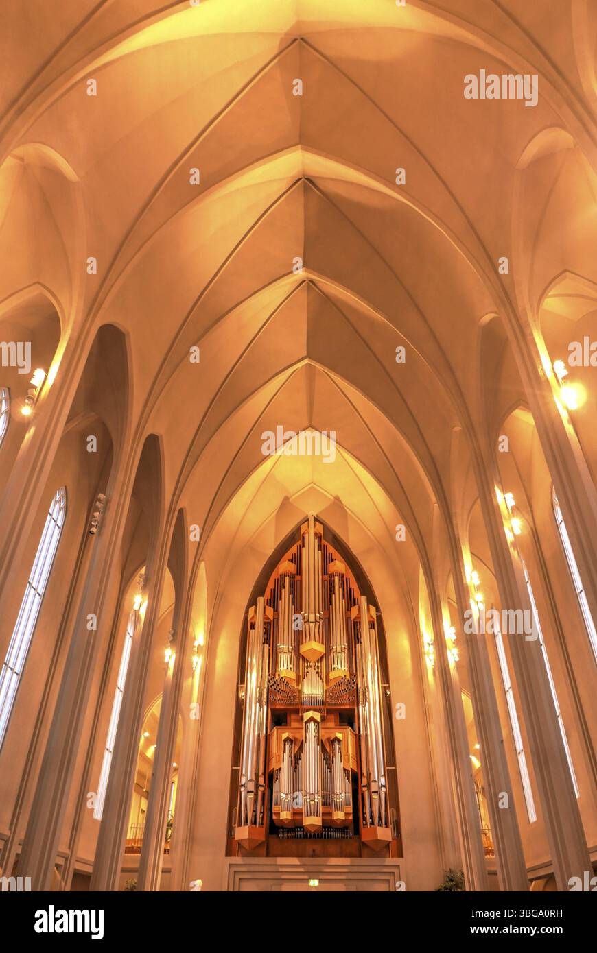 Hallgrimskirkja, avec sa flèche imposante, domine l'horizon de Reykjavik. Son design moderniste, l'intérieur de l'église dans une lumière jaune chaude Banque D'Images