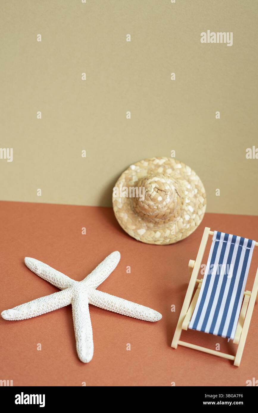Concept de plage de vacances d'été. Lit de soleil, étoile de mer, chapeau de paille sur fond rouge et beige kaki Banque D'Images