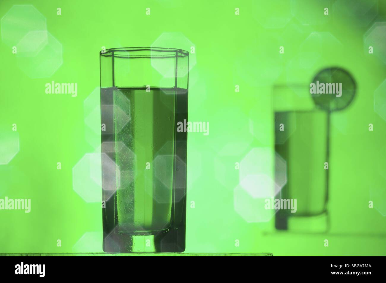 Nature morte avec verre de limonade rempli en premier plan et verre de limonade avec tranche de chaux en arrière-plan flou avec reflets éblouissants devant Banque D'Images