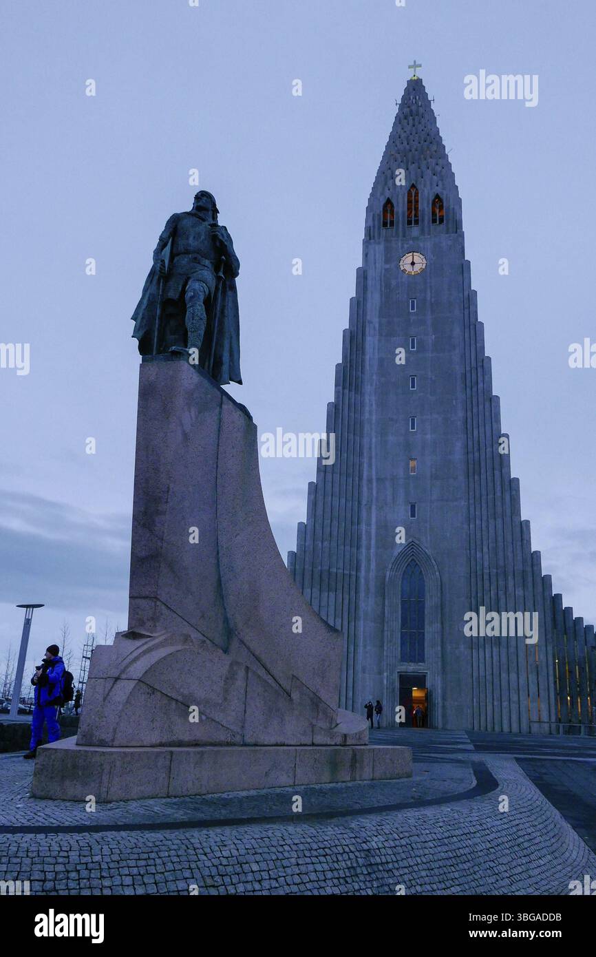 Hallgrimskirkja, avec sa flèche imposante, domine l'horizon de Reykjavik. Son design moderniste, tour de l'église avec horloge après le coucher du soleil Banque D'Images