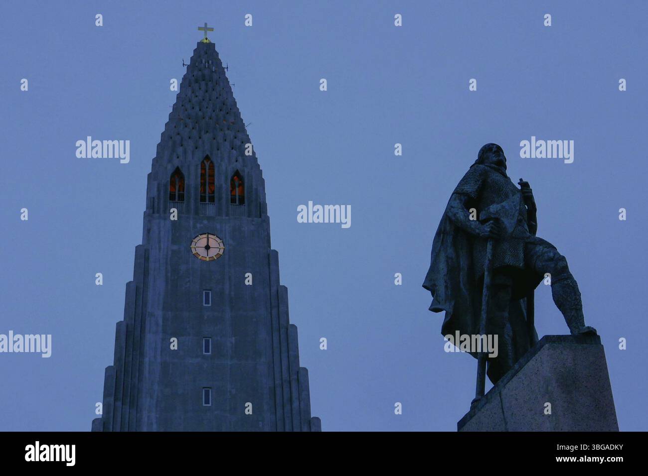Hallgrimskirkja, avec sa flèche imposante, domine l'horizon de Reykjavik. Son design moderniste, tour de l'église avec horloge après le coucher du soleil Banque D'Images