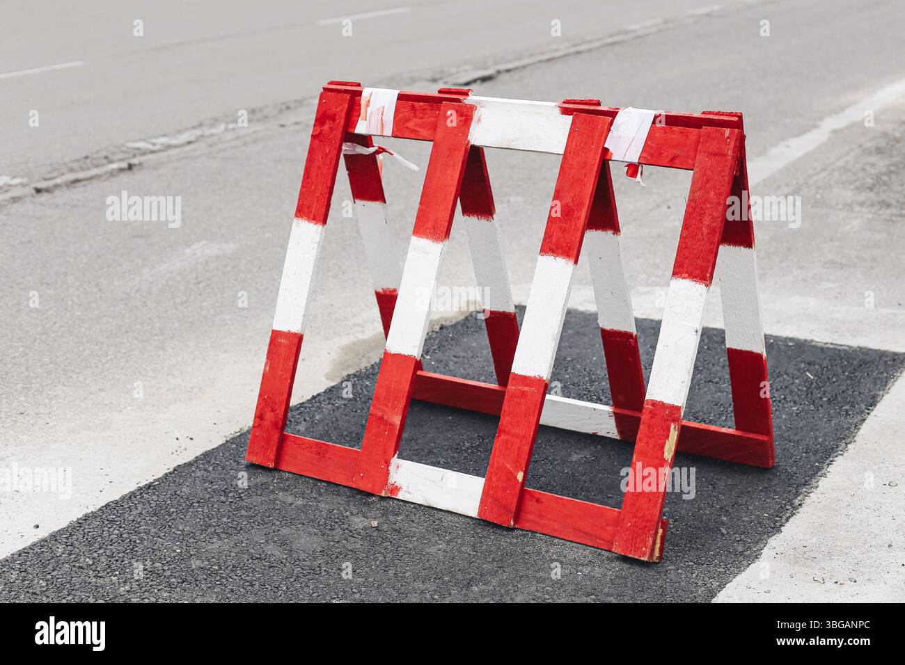 Barrière routière rouge et blanche. Obstacle de rue pour la sécurité routière. Zone de construction bloquant un passage. Site de réparation urbain avec surface asphaltée. Banque D'Images