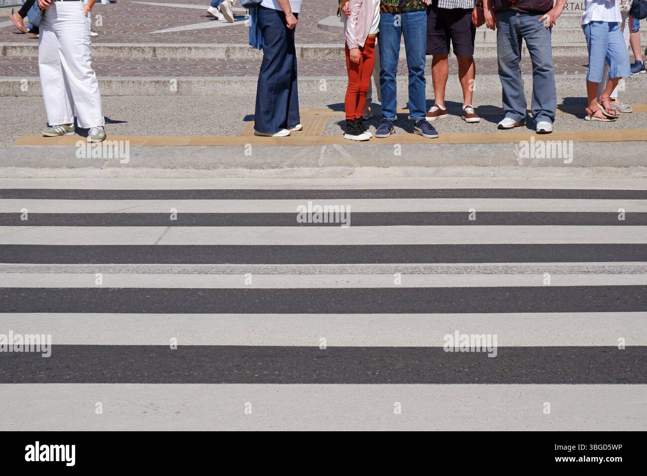 Section basse d'un groupe de personnes debout au carrefour et attendant de traverser la rue de la ville, Côme, Italie Banque D'Images