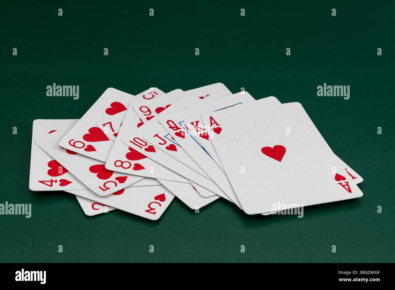 Cartes à jouer coeur dispersé sur la table de poker avec fond vert Banque D'Images