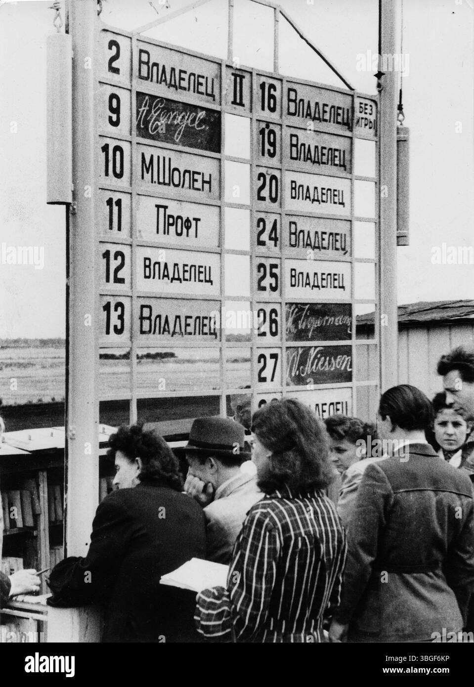 Russische Besucher betrachten eine Anzeigetafel mit Namen deutscher Fahrer – zur Verständigung werden deren Namen in kyrillischer und lateinischer Schrift dargestellt. Banque D'Images