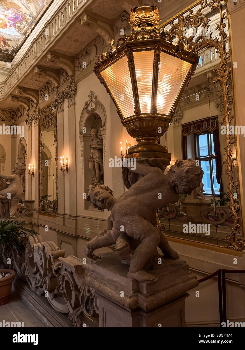 Somptueux intérieur baroque d'un palais viennois historique, orné de lanternes dorées ornées, de sculptures putto et de murs décorés avec soin Banque D'Images