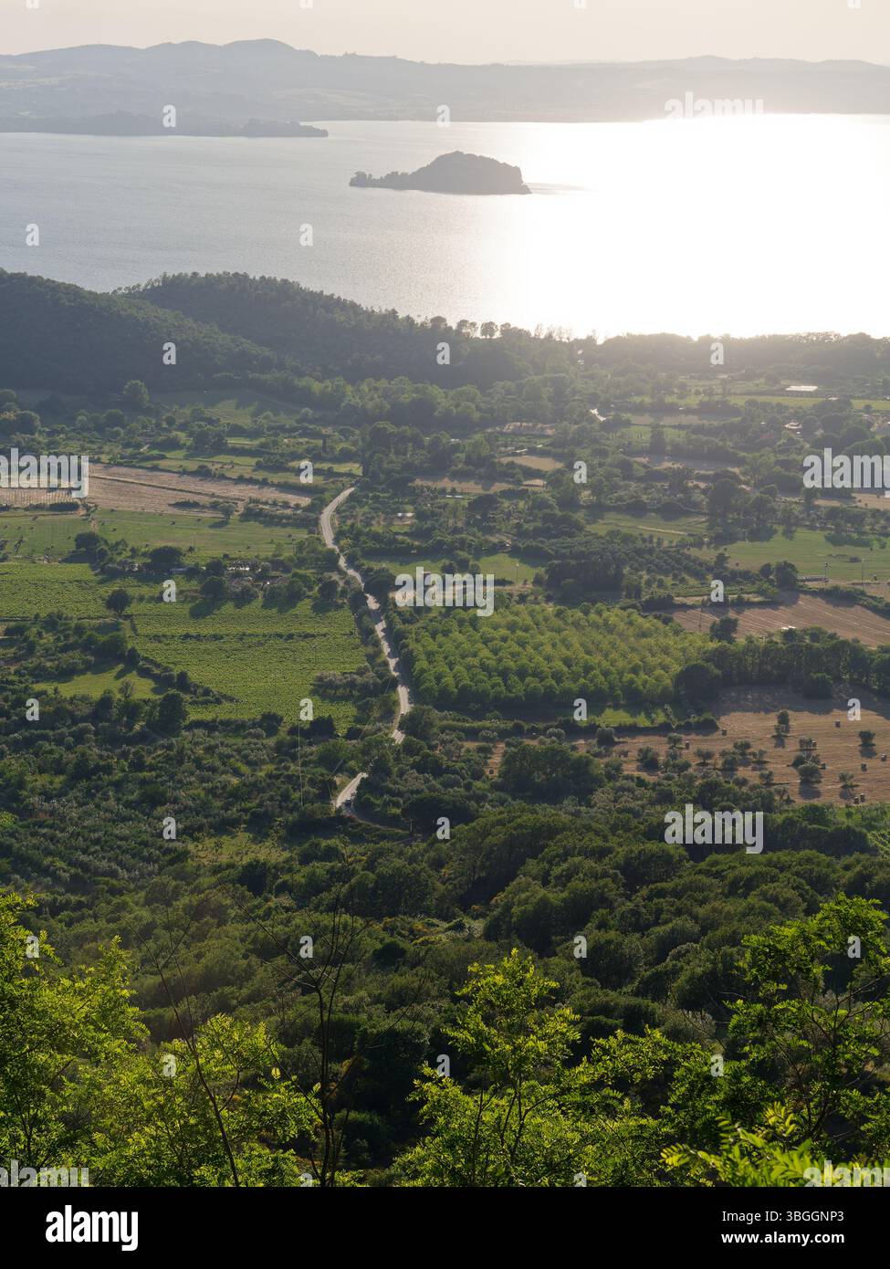 Vue aérienne de terres agricoles rurales et d'une route menant au lac Bolsena avec un centre de l'île. Montefiascone, région du Latium, Italie. 3 juin 2025 Banque D'Images