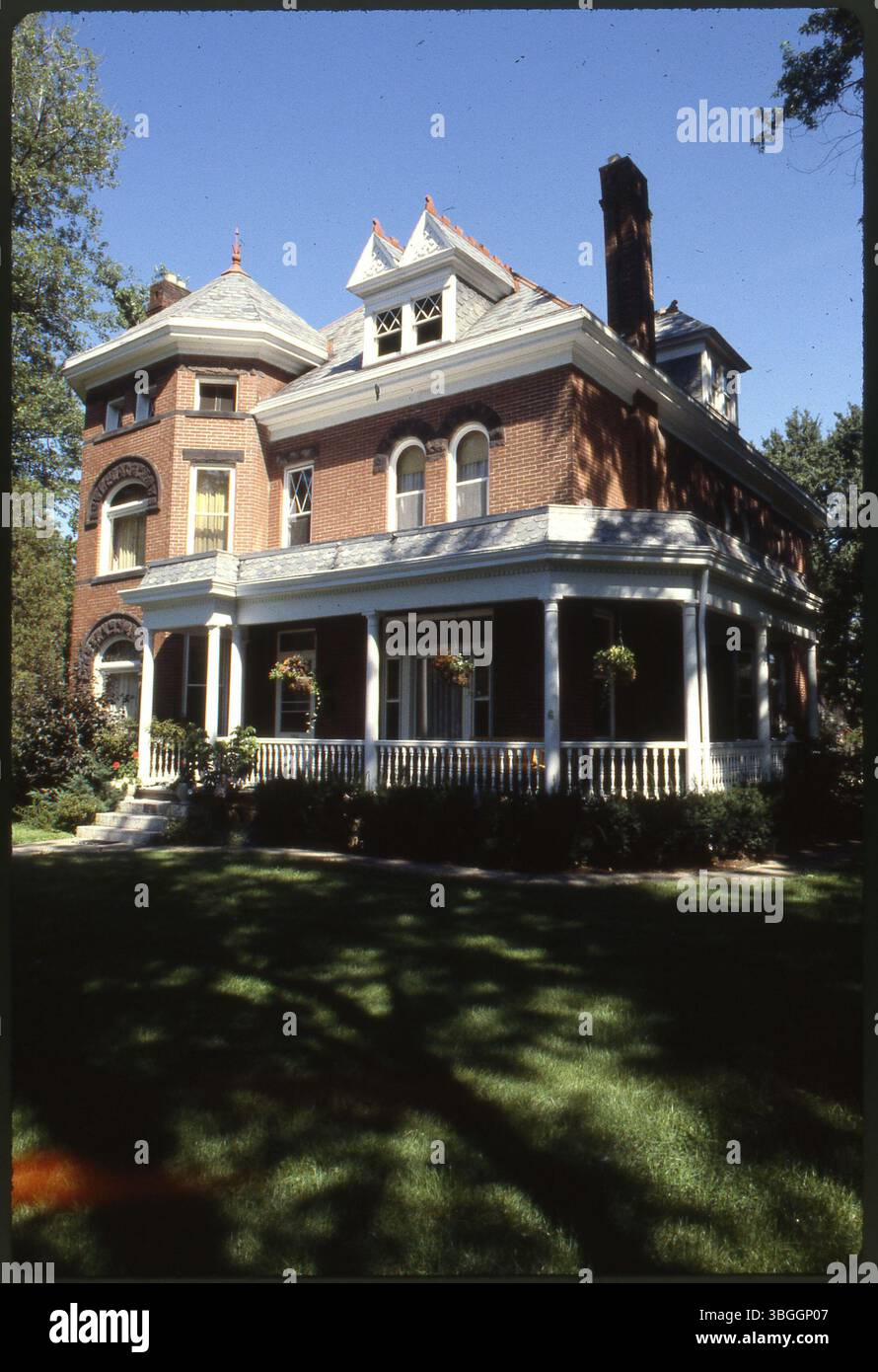 Une grande maison en briques de trois étages avec des fenêtres cintrées et un porche enveloppant. La maison n'est pas identifiée, et ses caractéristiques architecturales comprennent un extérieur en briques classique et des fenêtres cintrées distinctives. Banque D'Images