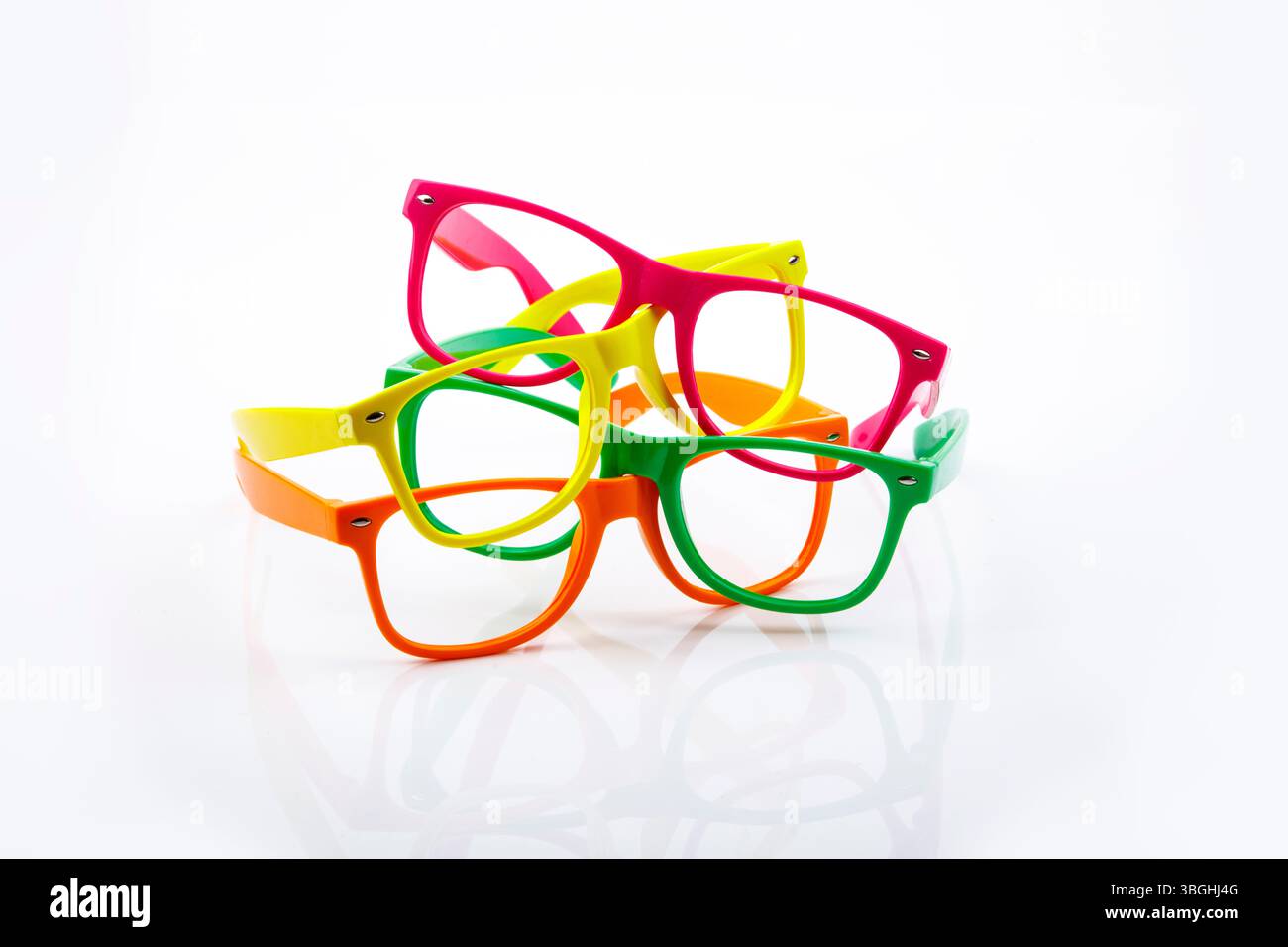 Des lunettes vibrantes de différentes couleurs créent une composition ludique sur une surface blanche réfléchissante. Banque D'Images