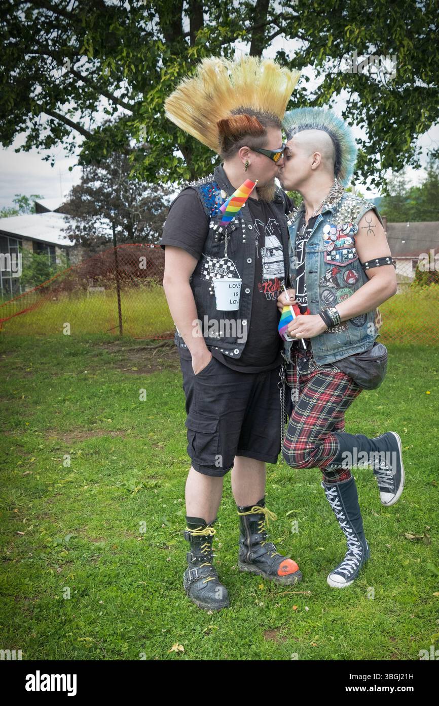 Un couple gay avec de hautes coiffures mohawk partagent un baiser à l'afterparty New Paltz Pride Parade 2025 à Hasbrouk Park. Banque D'Images