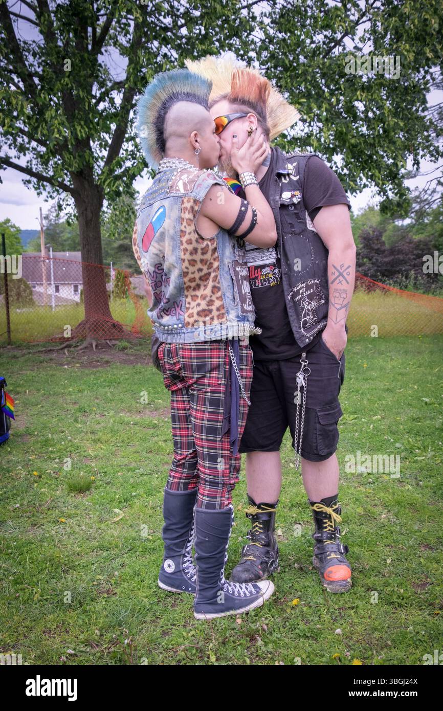 Un couple gay avec de hautes coiffures mohawk partagent un baiser à l'afterparty New Paltz Pride Parade 2025 à Hasbrouk Park. Banque D'Images