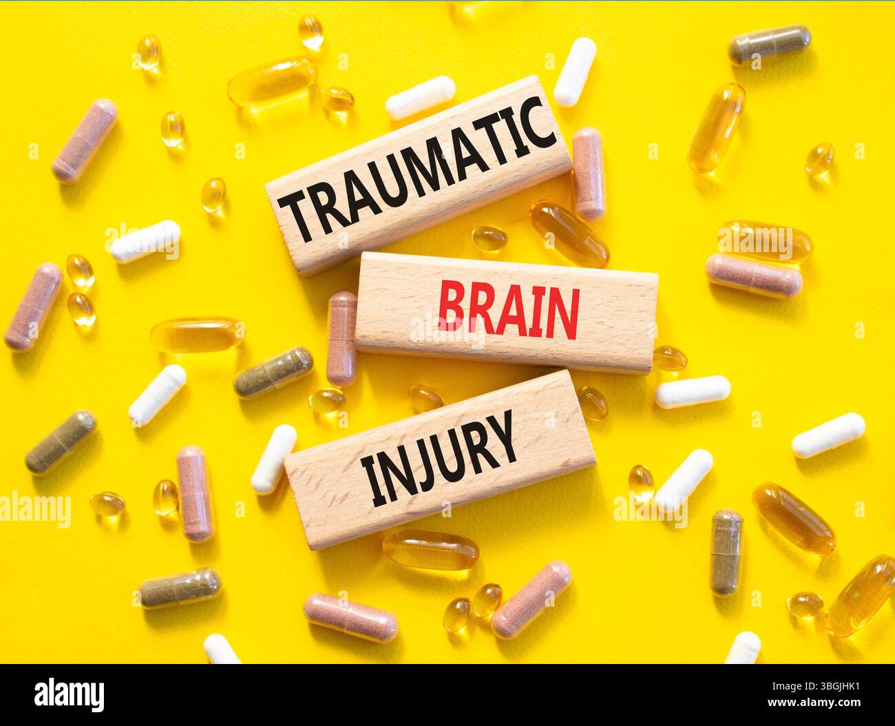 Symbole de lésion cérébrale traumatique. Mots conceptuels traumatisme crânien sur blocs de bois. Beau fond jaune avec des pilules. Soins de santé et traumatisme Banque D'Images