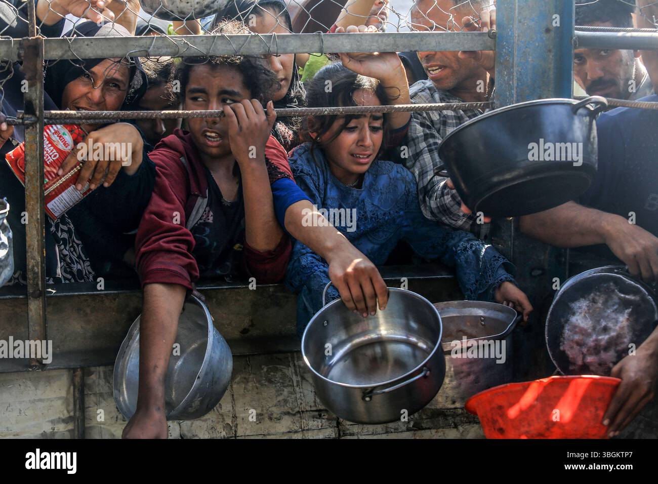 Les Palestiniens se rassemblent pour recevoir des repas chauds distribués par des organisations caritatives dans la zone Al-Mawasi de Khan Yunis, Gaza, le jeudi 5 juin 2025. Photo de Anas Deeb/UPI Banque D'Images