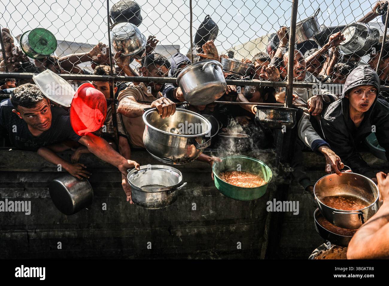 Les Palestiniens se rassemblent pour recevoir des repas chauds distribués par des organisations caritatives dans la zone Al-Mawasi de Khan Yunis, Gaza, le jeudi 5 juin 2025. Photo de Anas Deeb/UPI Banque D'Images