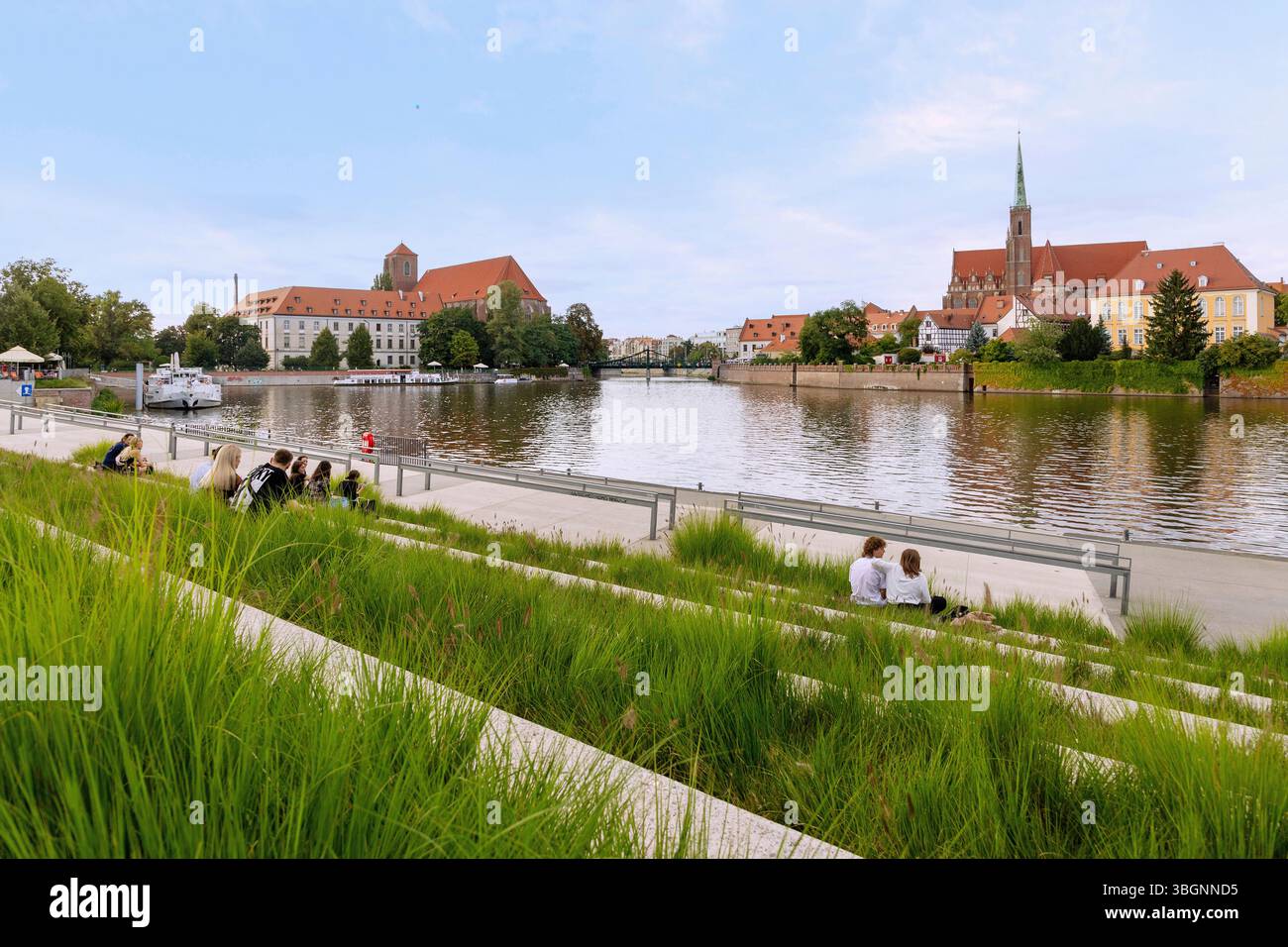 Terrasse du bord de mer à l'amphithéâtre de la marina (Przystan Amfiteatralna) sur l'Oder (Odra) avec vue sur l'île Cathédrale (Ostrow Tumski) avec l'église de la Sainte Croix (Doppelkirche zum Heiligen Kreuz und zum hl. Bartholomew, Kolegiata pw Swietego Krzyza i Swietego Bartlomieja) et Sand Island (Wyspa Piasek) Bibliothèque universitaire (Biblioteka Uniwersytecka) et l'église de Marie sur le sable (Sand-Kirche, Kosciol Najswietszej Marii Panny na Piasku, Kool Najswietszej Marii Panny na Piasku) Banque D'Images