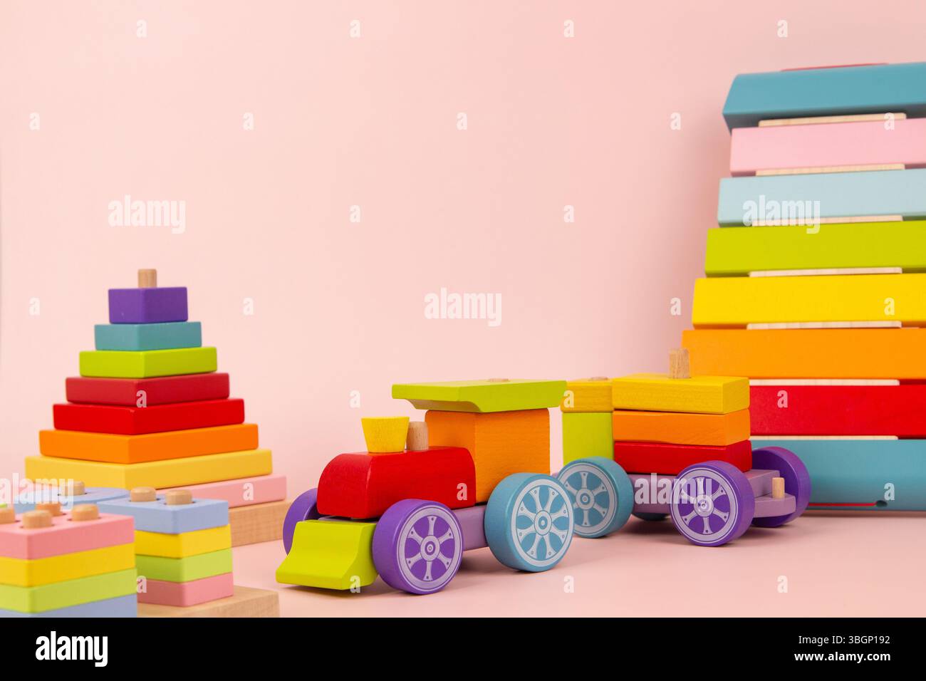 Fond de jouets pour bébés. Jouets éducatifs et musicaux en bois Montessori pour l'éducation précoce. Train en bois, xylophone, pyramide empilable sur fond rose Banque D'Images