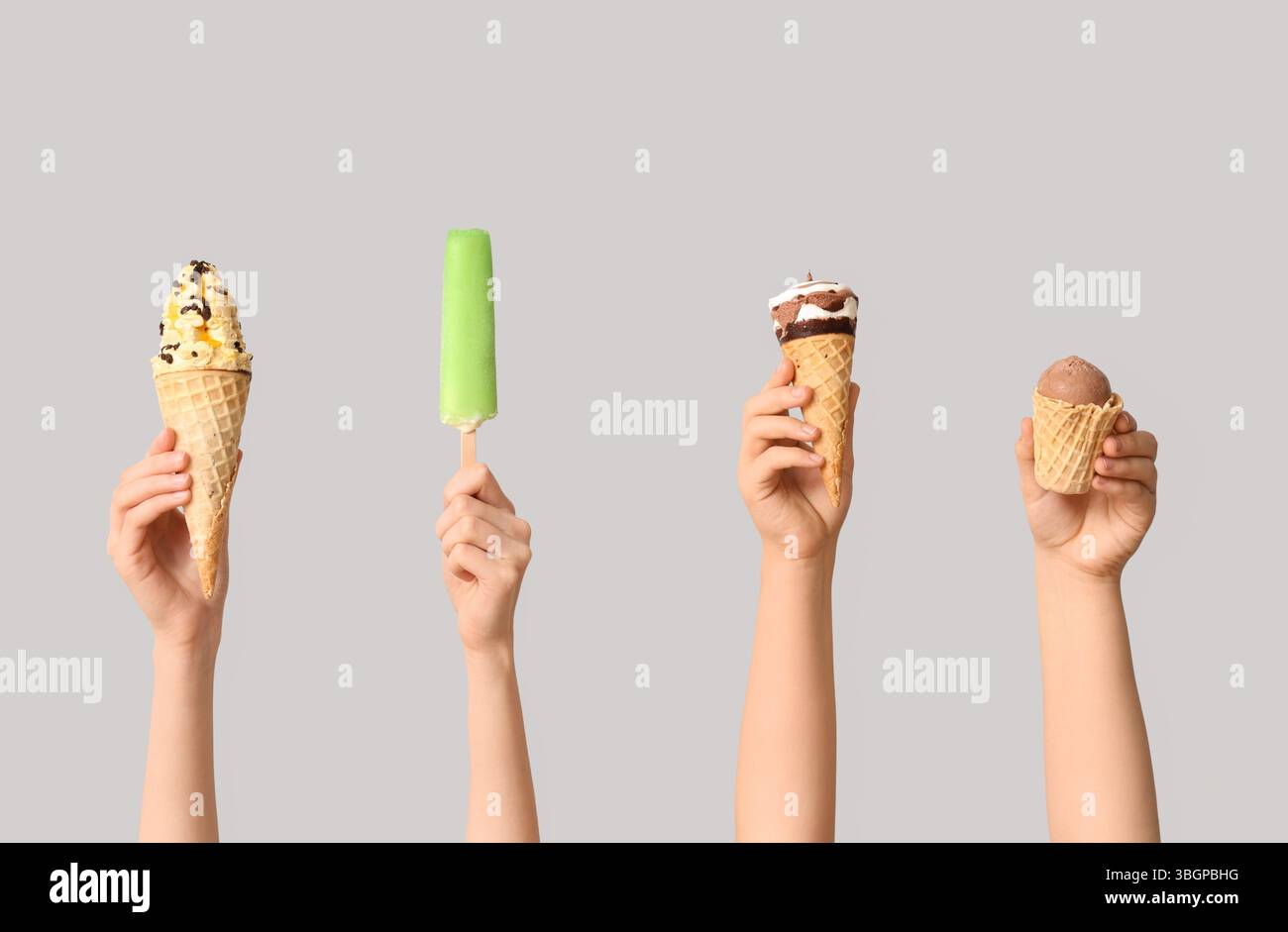 Mains féminines avec différentes glaces sucrées sur fond gris Banque D'Images