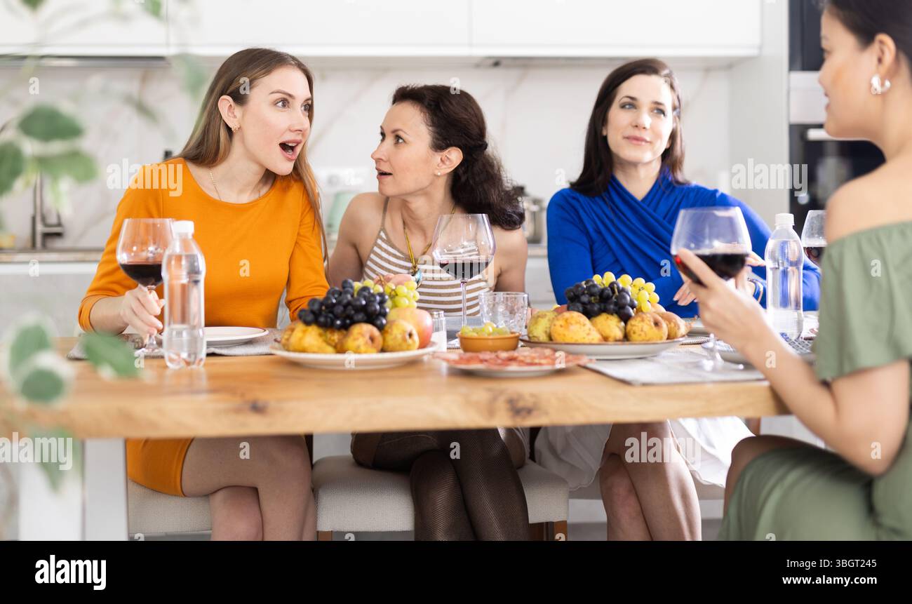 Des femmes heureuses se sont rassemblées autour d'une table festive ; participant à des discussions animées et appréciant les délices du vin Banque D'Images