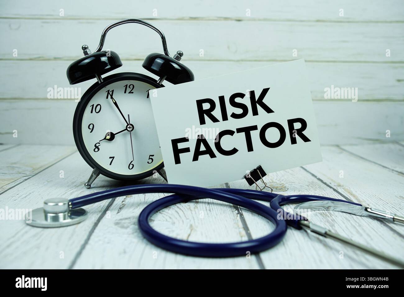 Texte de facteur de risque sur carte papier avec réveil et stéthoscope sur fond en bois Banque D'Images