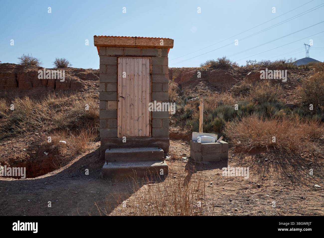 Toilettes extérieures à la campagne. Cabine de toilettes à blocs de béton avec porte en bois. Banque D'Images