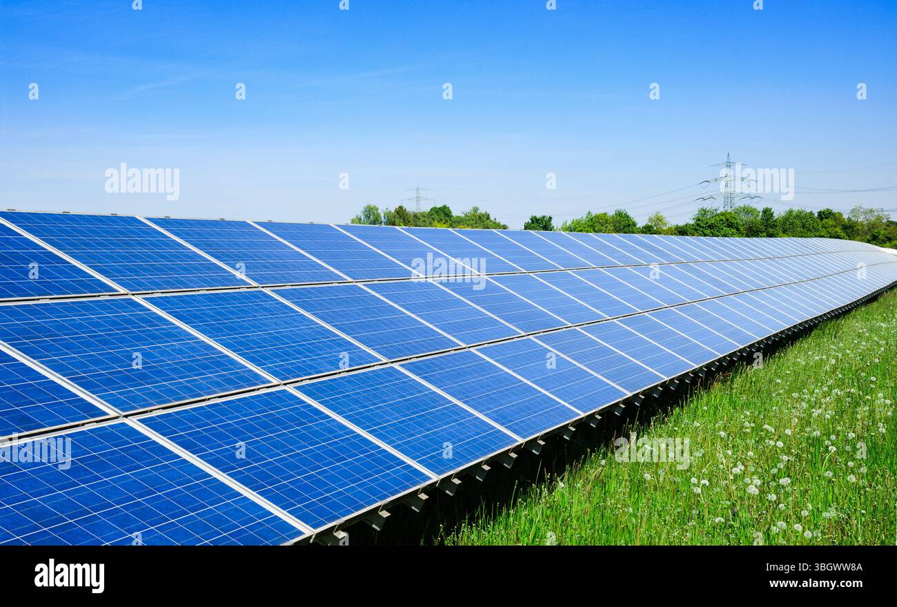 Un système solaire moderne dans un paysage verdoyant avec une ligne électrique à haute tension en arrière-plan, montrent les progrès de la production d'énergie durable et th Banque D'Images