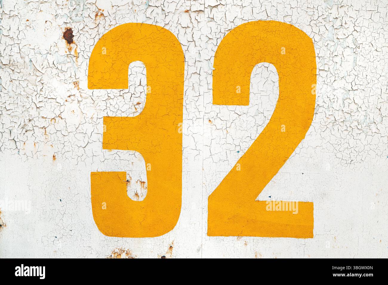 Numéro jaune trente-deux sur le mur blanc grunge comme fond Banque D'Images