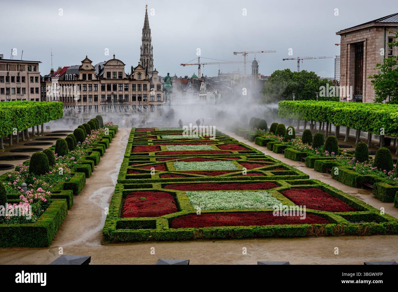 Le jardin du Mont des Arts à Bruxelles avec des arroseurs d'eau pulvérisant sur des haies et des parterres de fleurs soigneusement taillés Banque D'Images