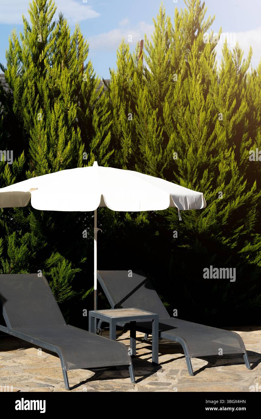 Deux chaises longues dans une maison en pierre avec un jardin au coucher du soleil Banque D'Images
