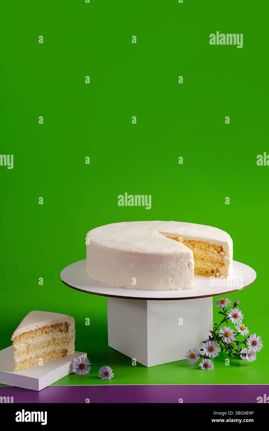 Un appétissant et délicieux gâteau à la vanille présenté magnifiquement sur un fond vert vif Banque D'Images