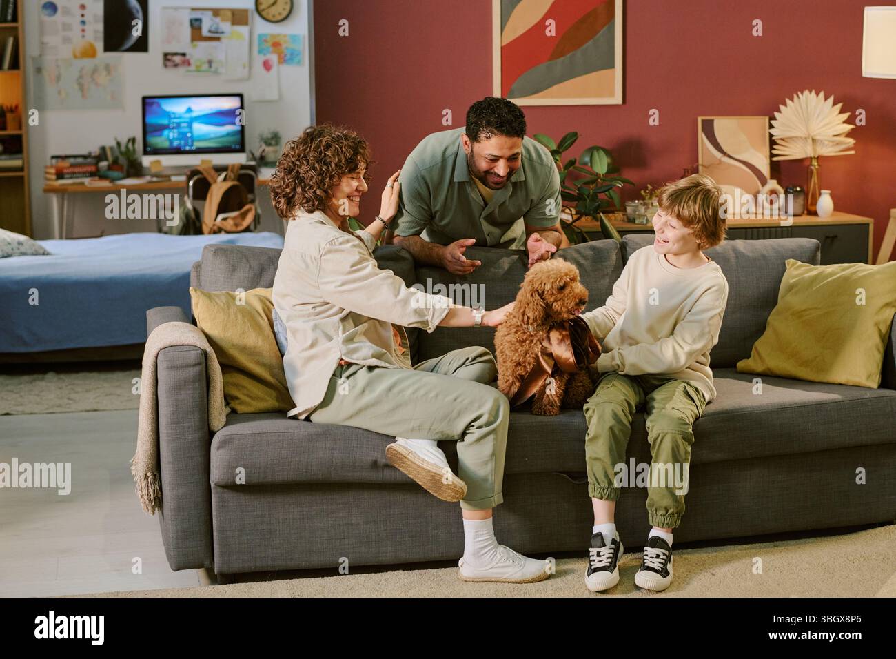 Enfant caucasien avec ses parents introduisant le premier chien de compagnie au salon à la maison Banque D'Images