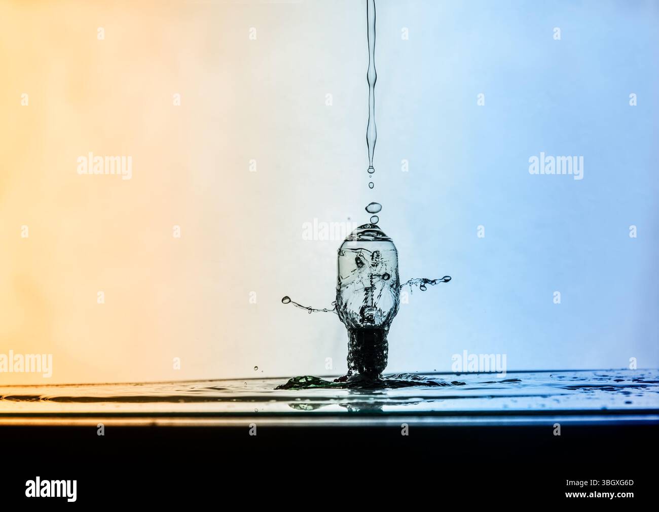 Une photographie ultra-rapide capture le moment où une goutte d'eau heurte une ampoule en verre, créant un effet éclaboussant et d'ondulation sur un fond noir dégradé Banque D'Images