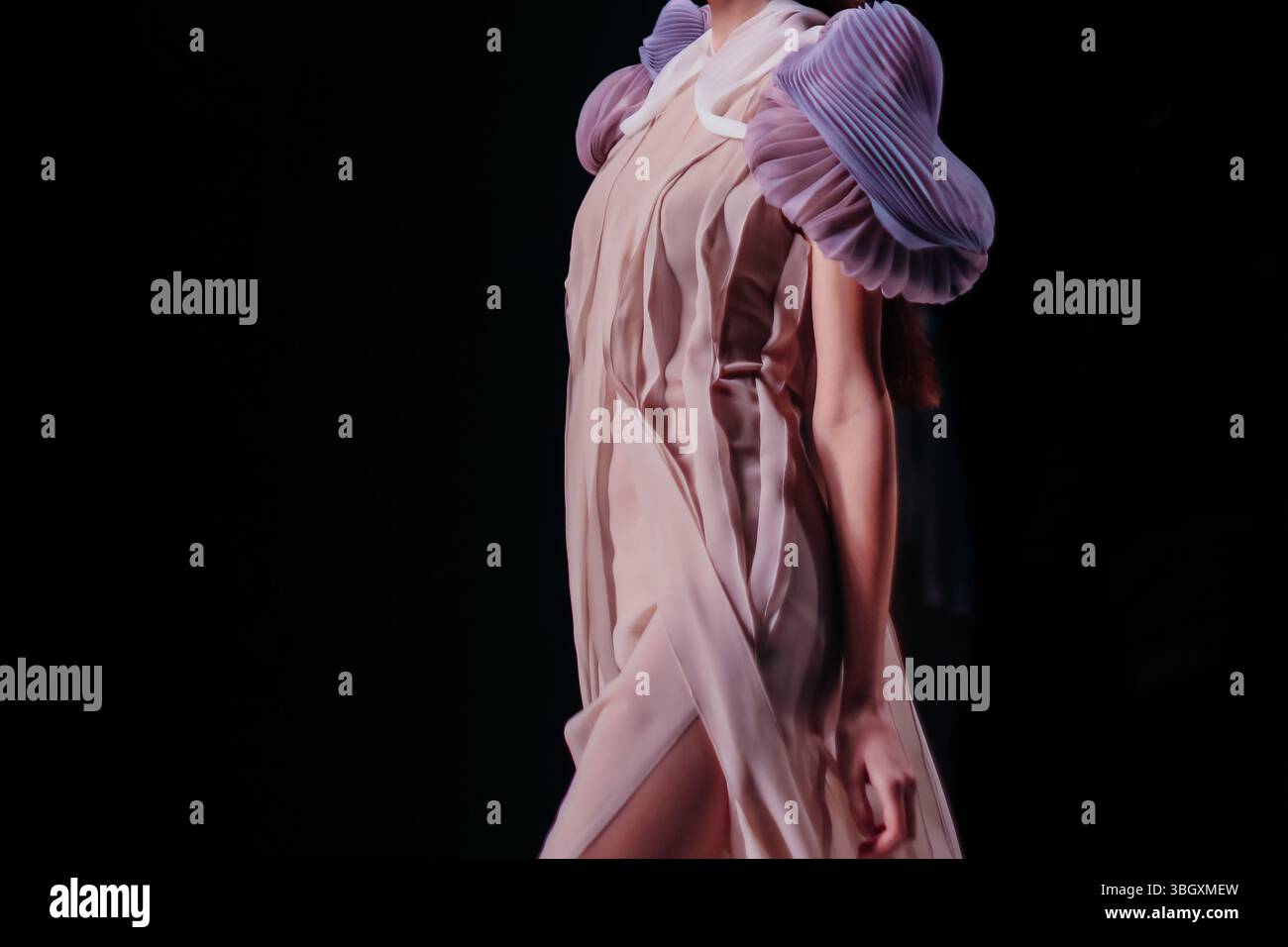 Robe en soie rose pastel sur fond noir. Mode femme et tissu élégant. Mannequin marchant le défilé de mode de la piste Banque D'Images