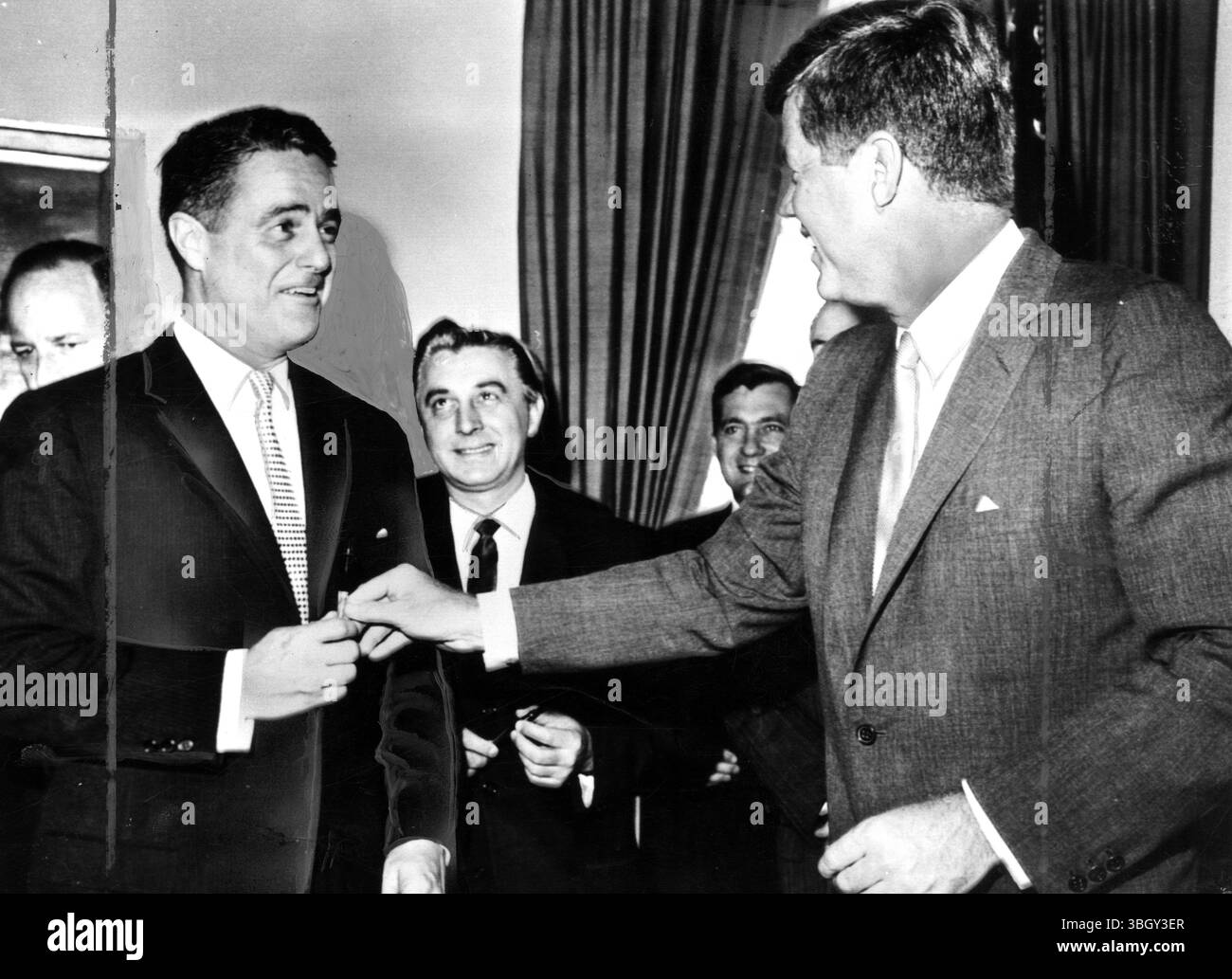 Le président Kennedy a signé un projet de loi donnant au Peace corps nouvellement formé un statut permanent. Ici, le chef de l'exécutif remet l'un des stylos utilisés lors de la cérémonie à son beau-frère Sargent Shriver, directeur du corps. Au centre se trouve le représentant Roman C Pucinski. 22 septembre 1961 Banque D'Images