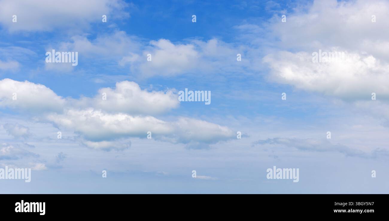 Des nuages de cumulus blancs légers et moelleux se dispersent à travers un ciel bleu vif, suggérant sérénité et tranquillité. Texture naturelle de la photo de fond Banque D'Images