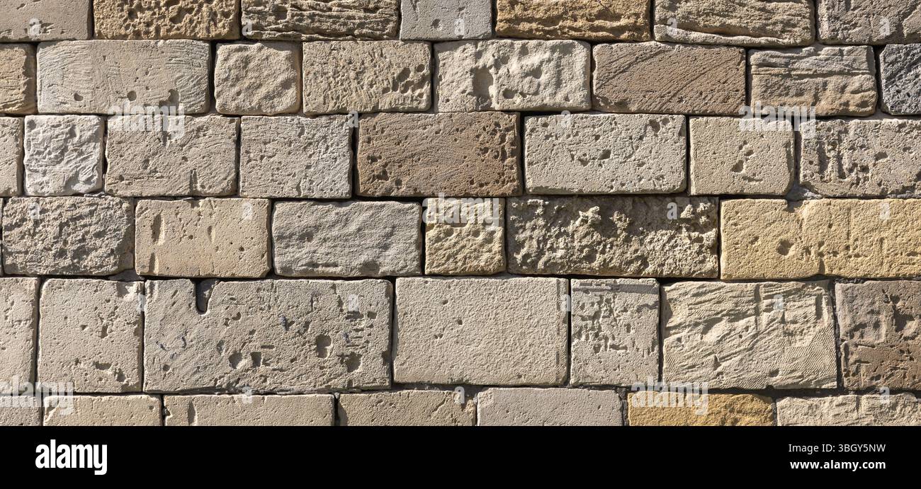 Gros plan de mur de briques de pierre texturées dans les tons neutres. Fond de photo panoramique abstrait Banque D'Images