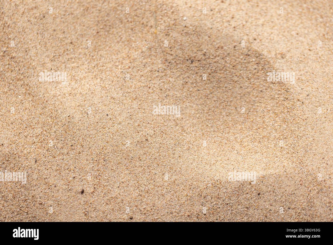 Vue détaillée du sable de quartz doré texturé sous éclairage naturel, mettant en valeur les grains et les motifs Banque D'Images