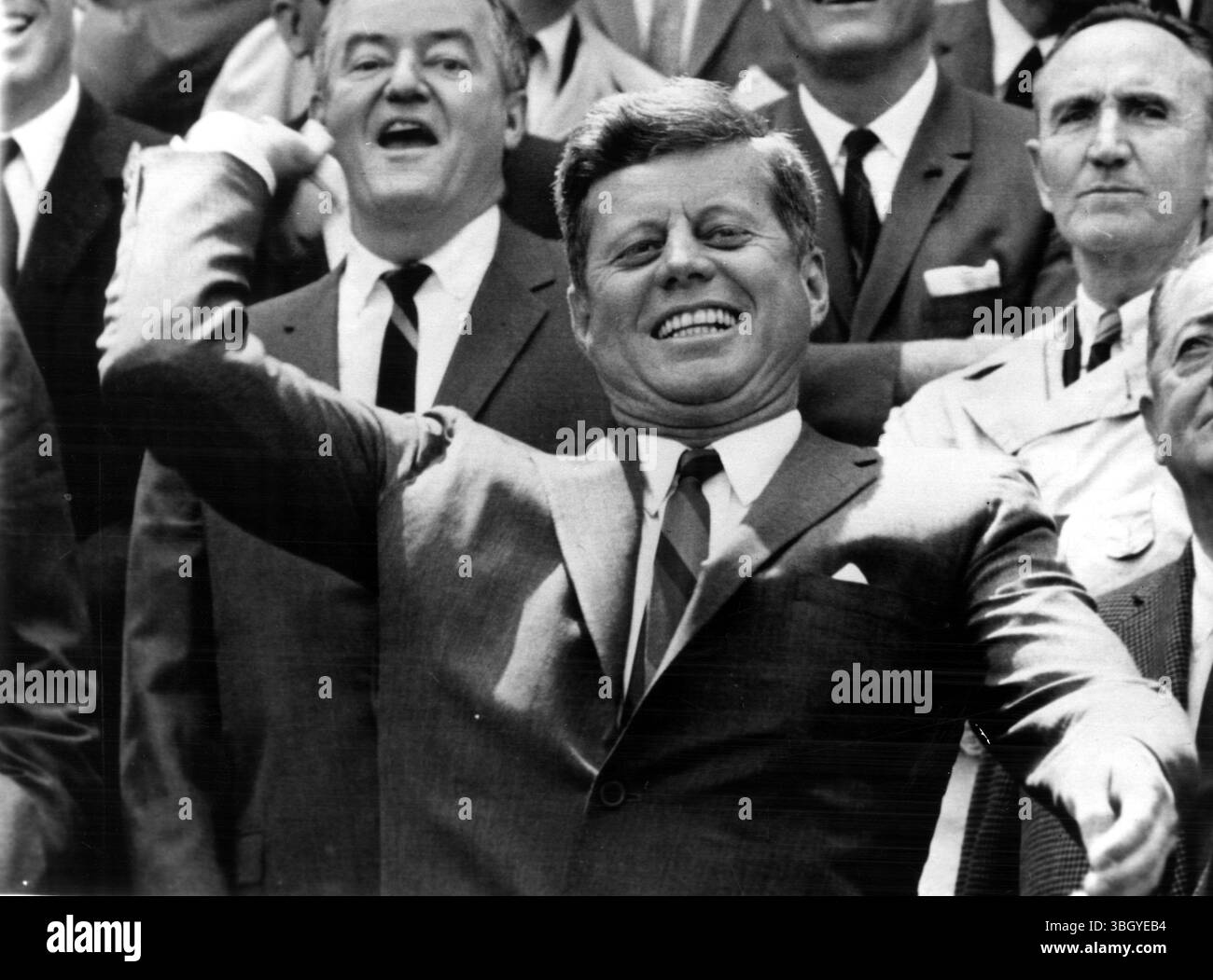 Le président John Fitzgerald Kennedy se réveille alors qu'il se prépare à faire le 1er pitch cérémoniel pour lever le rideau sur la saison de la Ligue majeure de baseball. Derrière le président (de gauche à droite), le sénateur Hubert Humphrey, le chef de la majorité au Sénat Mike Mansfield, et James M. Johnston, président du conseil d'administration des sénateurs de Washington. 8 avril 1963 Banque D'Images