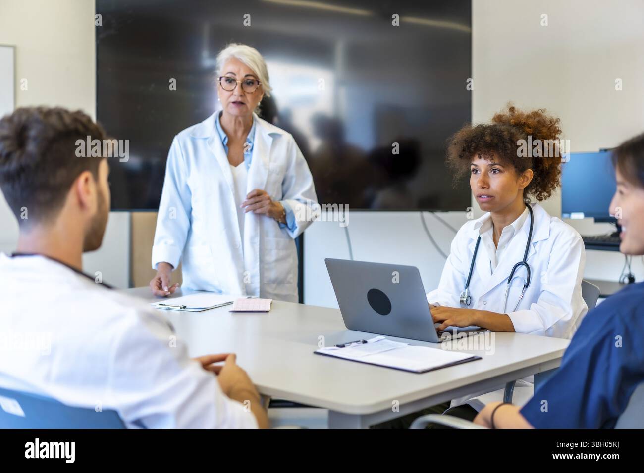 Médecins et professionnels de la santé collaborant, partageant leur expertise et analysant les informations des patients lors d’une réunion productive dans un hôpital moderne Banque D'Images