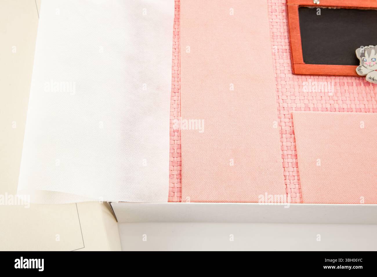 Vue rapprochée d'un album photo rose doté d'une feuille de protection, nichée dans une boîte blanche, soulignant sa volonté de préserver ses souvenirs précieux et ses projets créatifs Banque D'Images