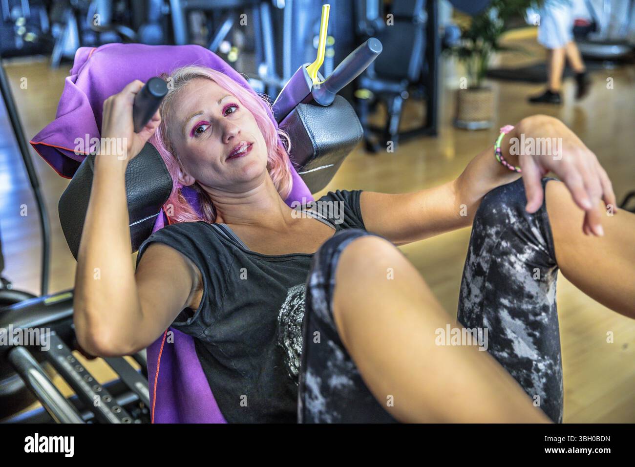 Athletic woman portrait in sportswear, s'accroupissant et en poussant sur ses jambes pour former la presse jambes machine dans sa salle de sport. Concept de vie sain. Fermer u Banque D'Images