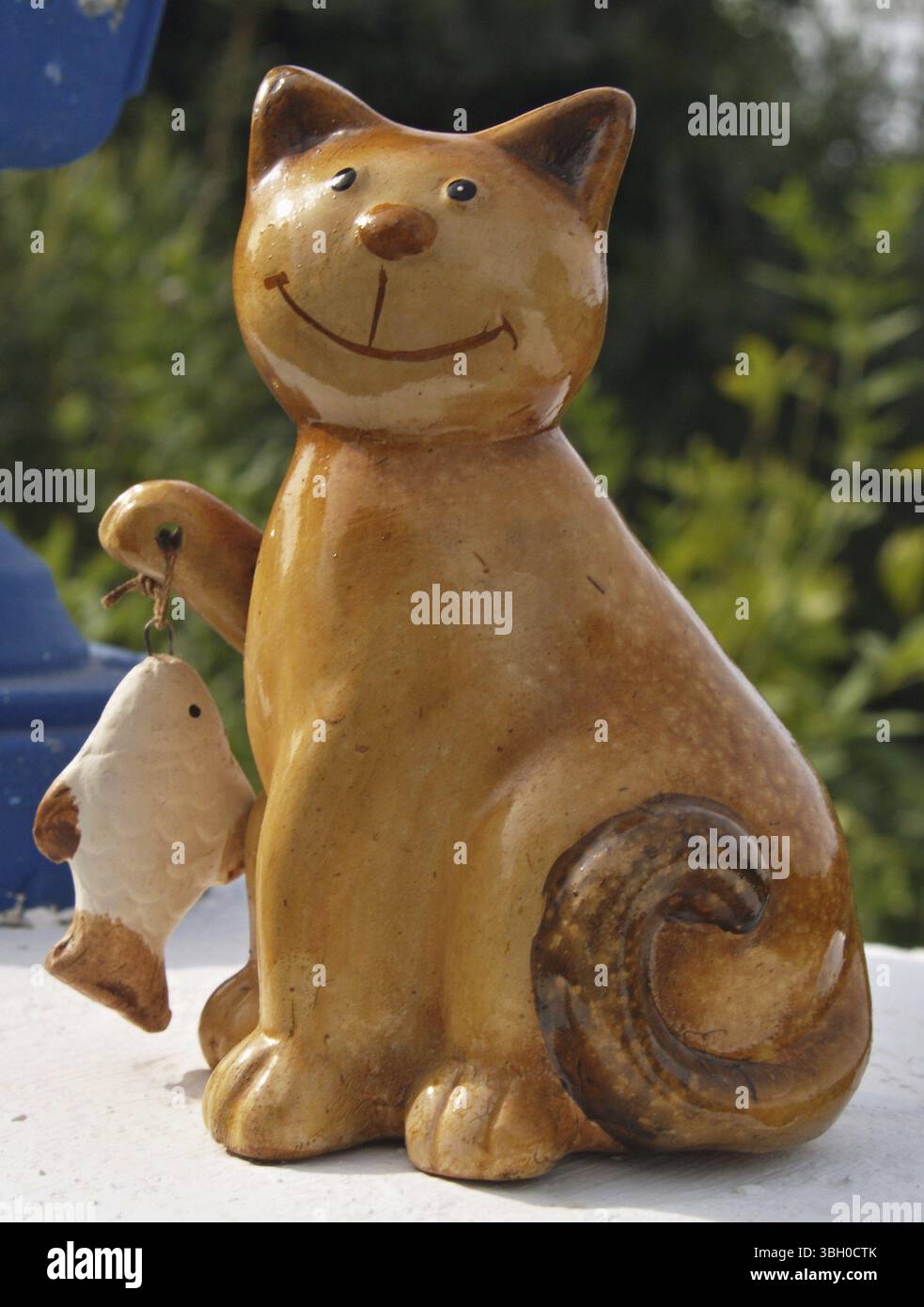 Chat marron drôle en céramique avec un poisson Banque D'Images