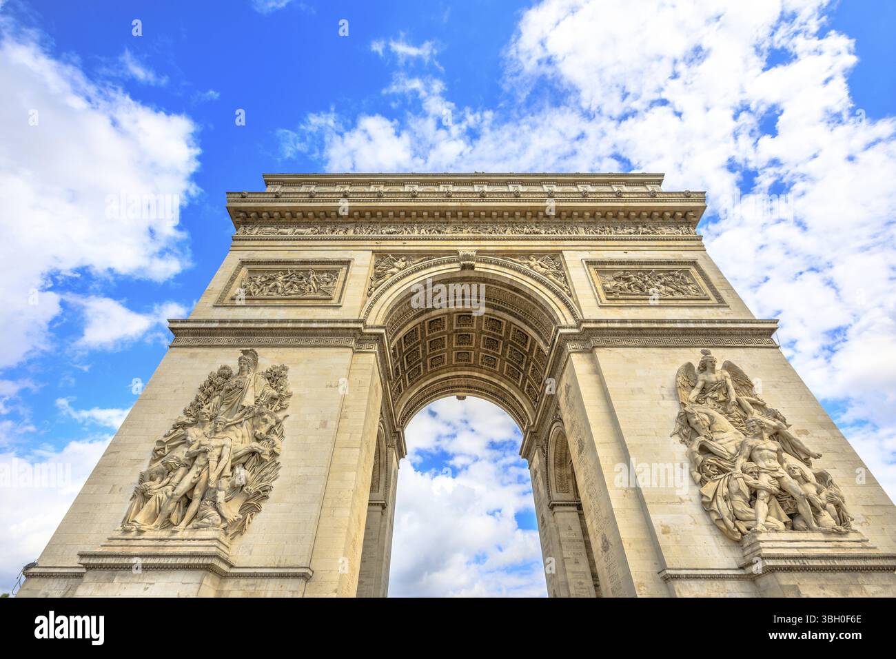 Vue de dessous de l'Arc de Triomphe au centre de la place Charles de Gaulle avec nuages et ciel bleu. Monument populaire et attraction touristique célèbre à Paris Banque D'Images