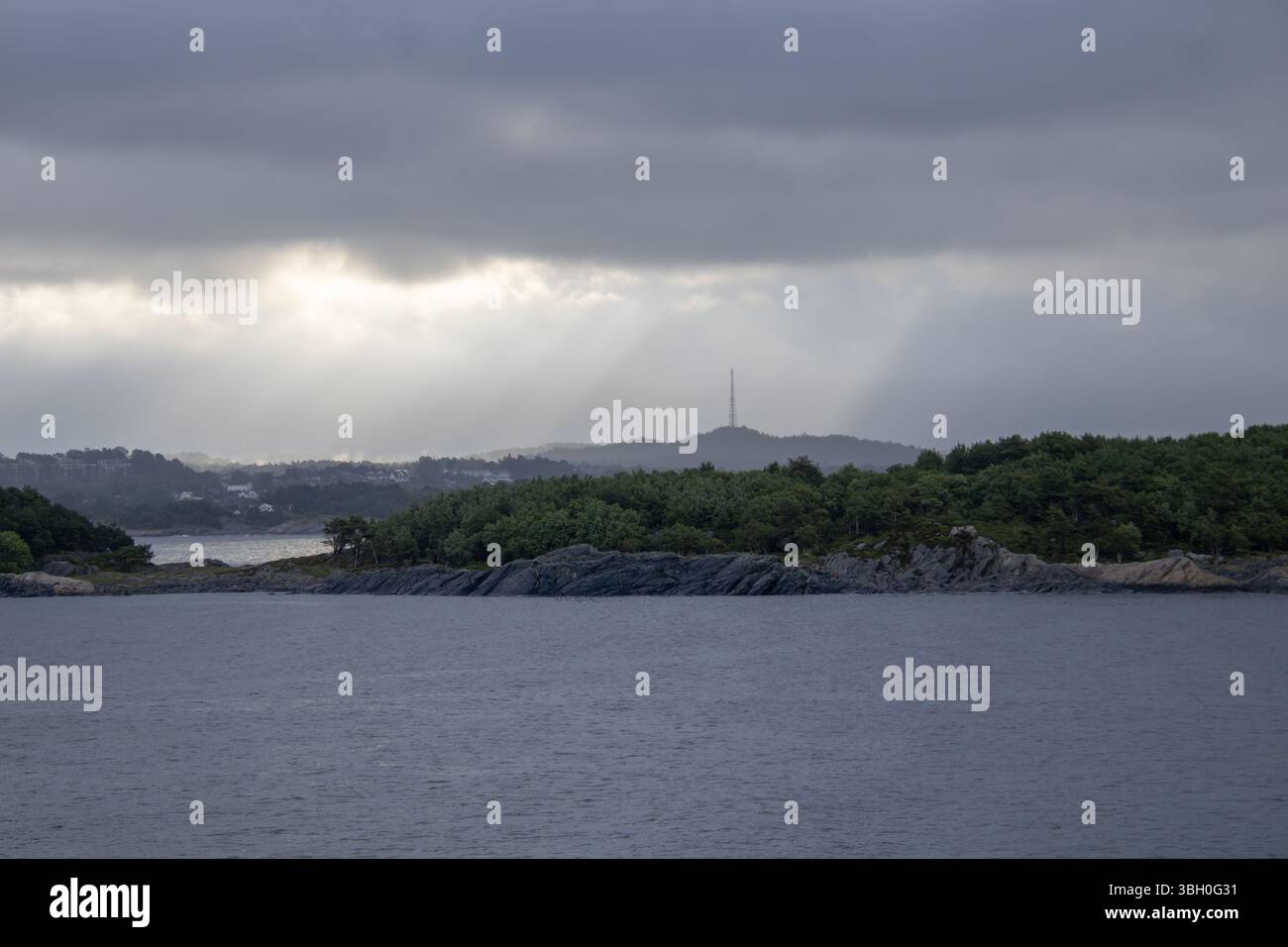 Norwegisches Küstenstädtchen mit Funkturm – Weiße Holzhäuser und bewaldete Hügel am Meer Banque D'Images
