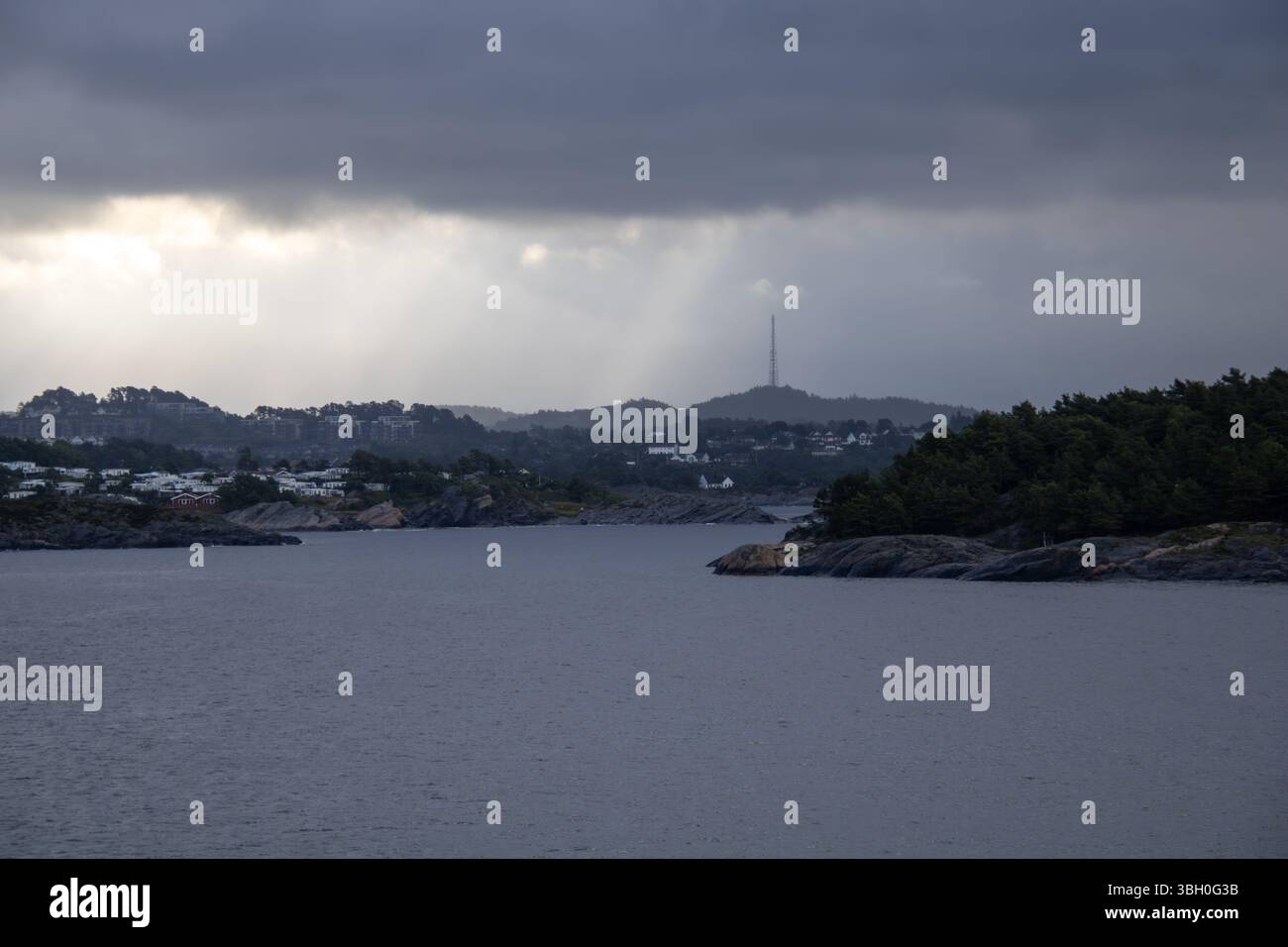 Norwegisches Küstenstädtchen mit Funkturm – Weiße Holzhäuser und bewaldete Hügel am Meer Banque D'Images