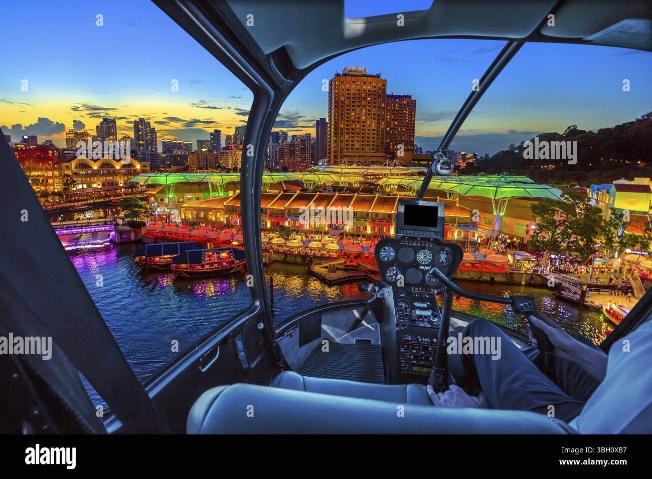 Hélicoptère cockpit intérieur volant sur la ligne d'horizon aérienne de Clarke Quay et la zone riveraine au coucher du soleil à Singapour, Asie du Sud-est. Horizon au bord de l'eau sur S Banque D'Images