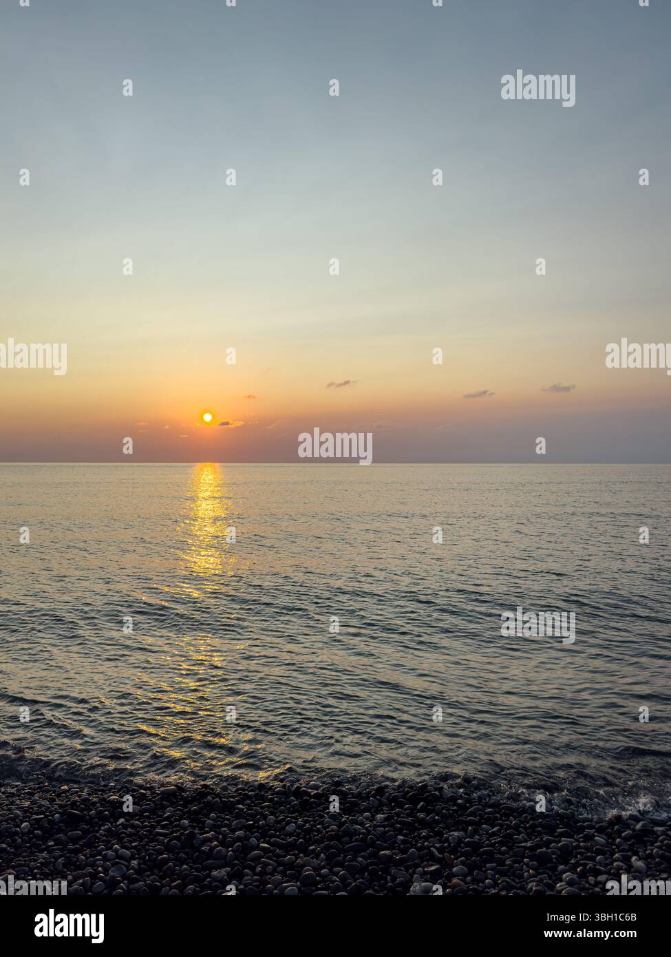 Coucher de soleil sur la mer Noire avec vagues calmes, ciel coloré et plage de galets à Batoumi, Géorgie. Convient pour les voyages, les milieux, la détente, la nature et le design. Banque D'Images