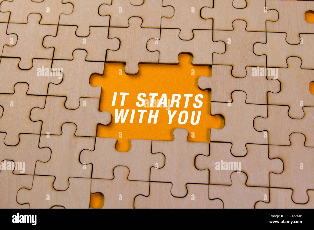 Pièces de puzzle en bois dans un cadre lumineux, mettant en valeur une citation sur la responsabilité personnelle et l'initiative. Banque D'Images