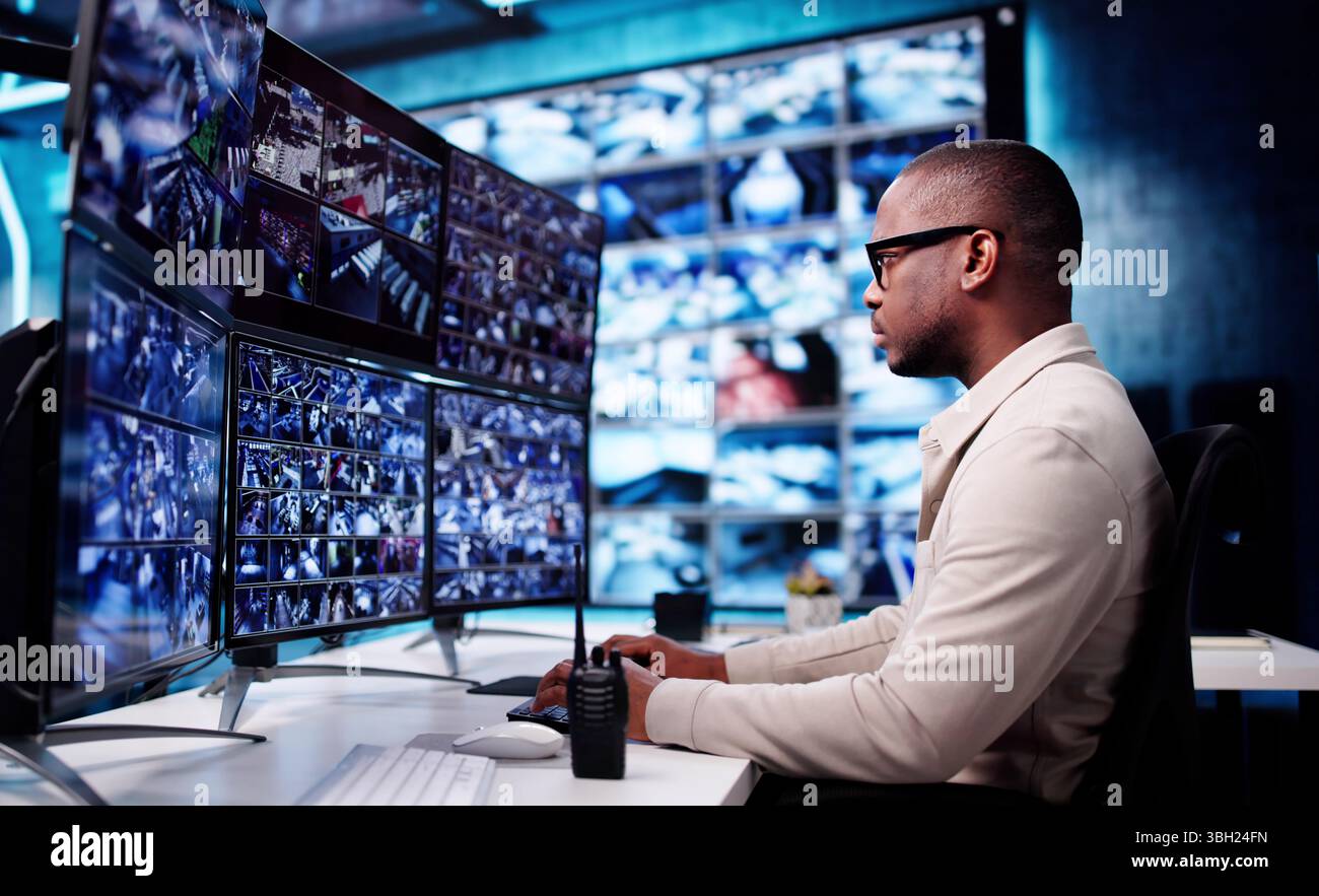 Un opérateur de vidéosurveillance afro-américain de sexe masculin surveille plusieurs écrans pour des vidéos de sécurité. Banque D'Images